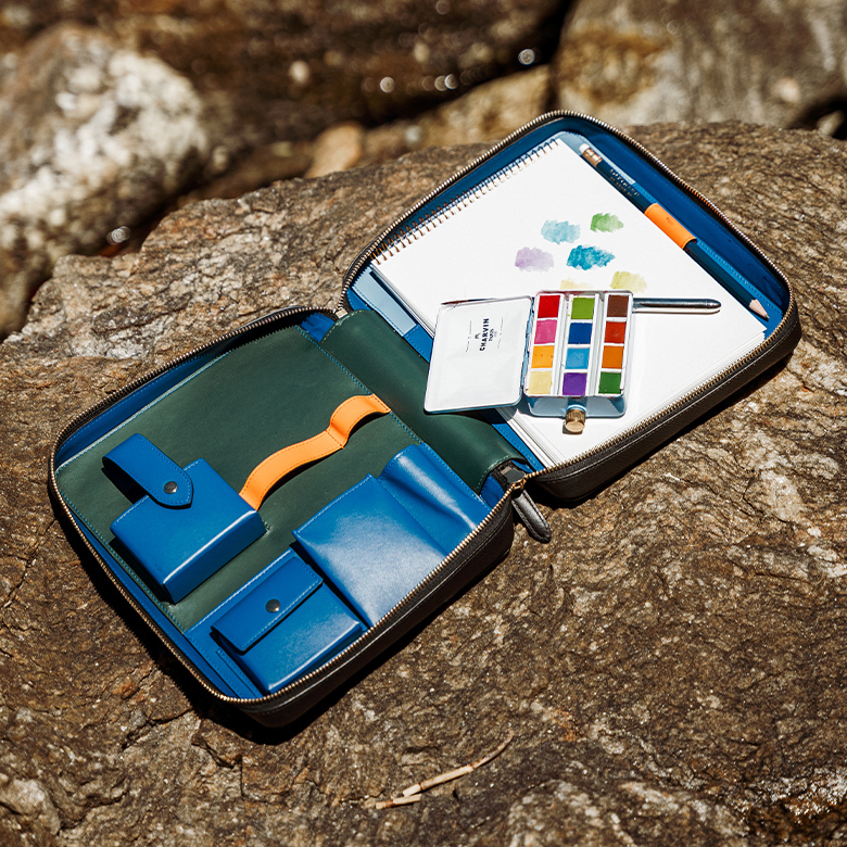 Das geöffnete Smythson Artist Folio mit Aquarellfarben, Pinsel und Bleistift